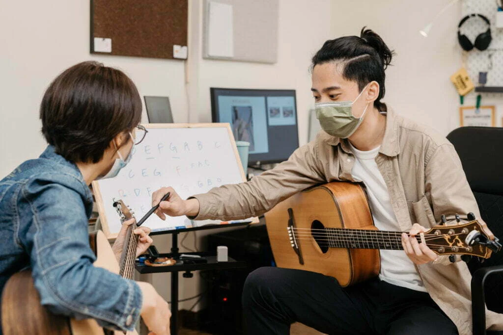 老師在課堂上協助學生調整吉他彈奏動作